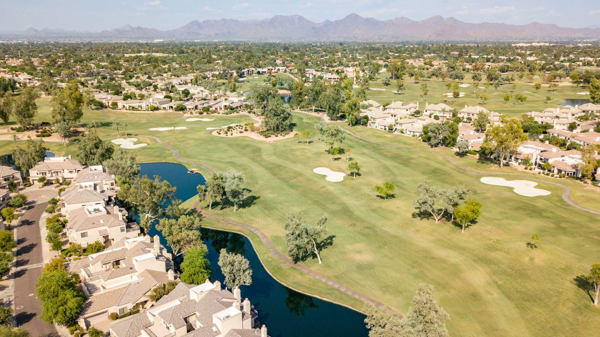 Aerial view of Gainey Ranch golf course, lakes and homes with mountains on the horizon, Scottsdale
