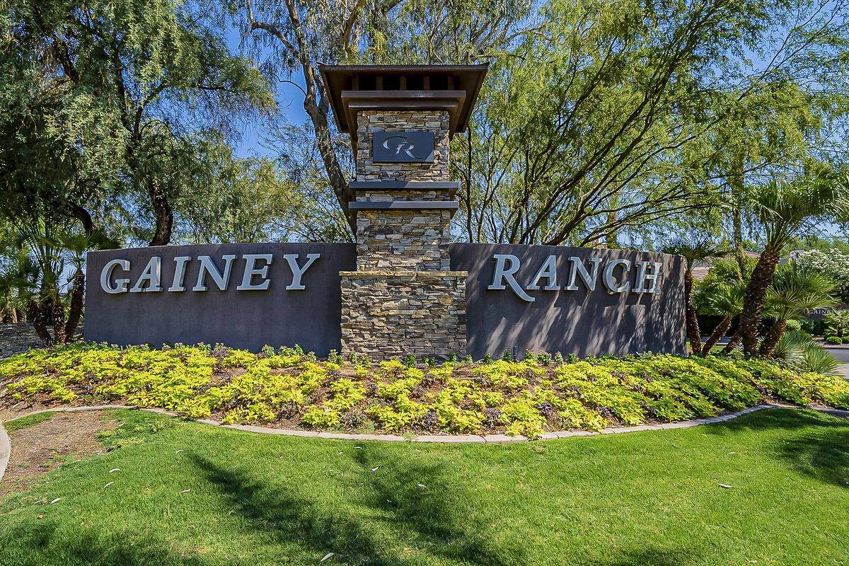 Gainey Ranch stone entry monument sign with landscaped flower bed and mature trees in Scottsdale, Arizona
