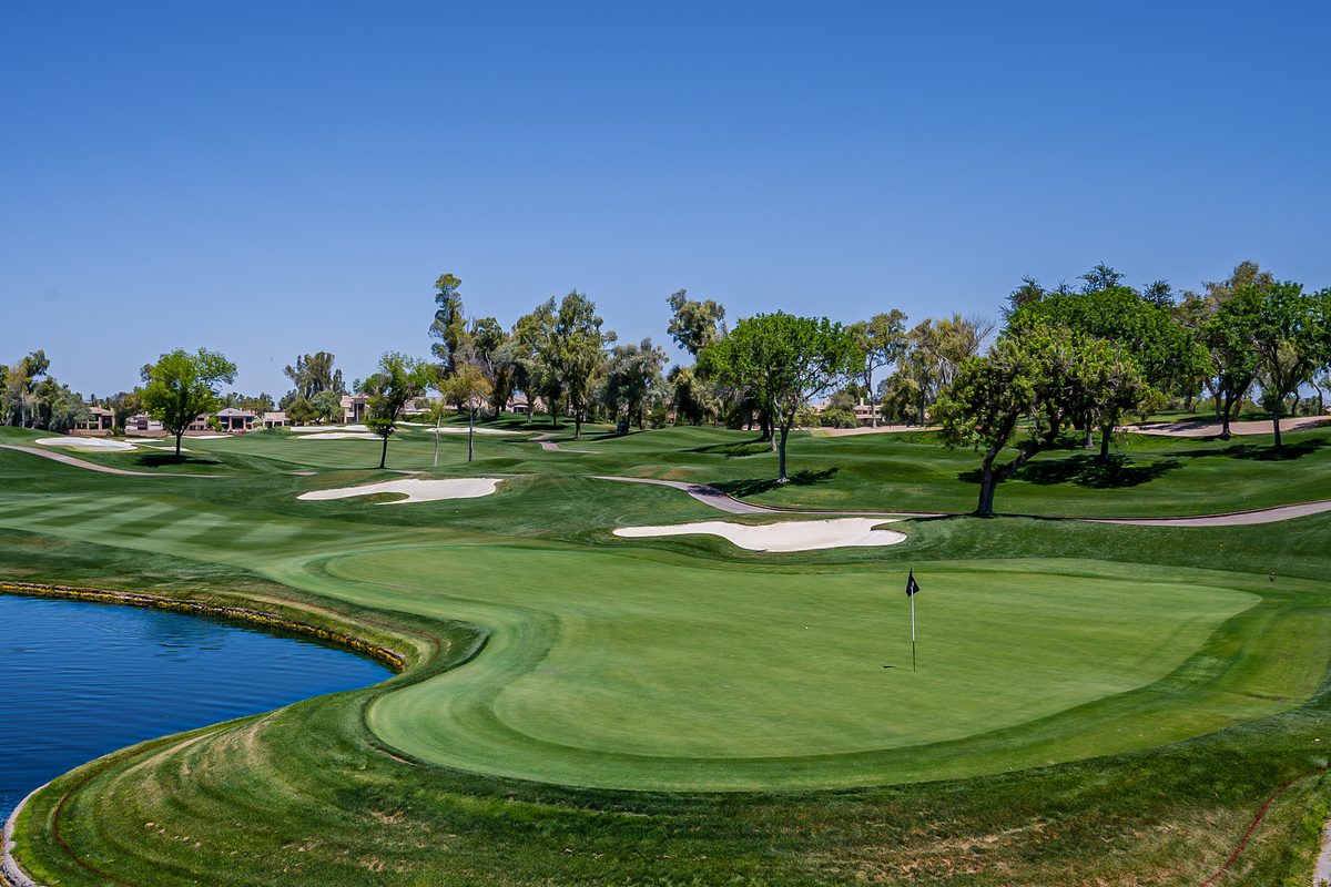 Golf green with a flag beside a water feature, bunkers and mature trees on a Gainey Ranch course in Scottsdale