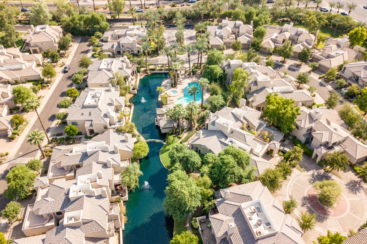 Aerial view of Gainey Ranch homes with tile roofs along a landscaped lagoon with fountains in Scottsdale