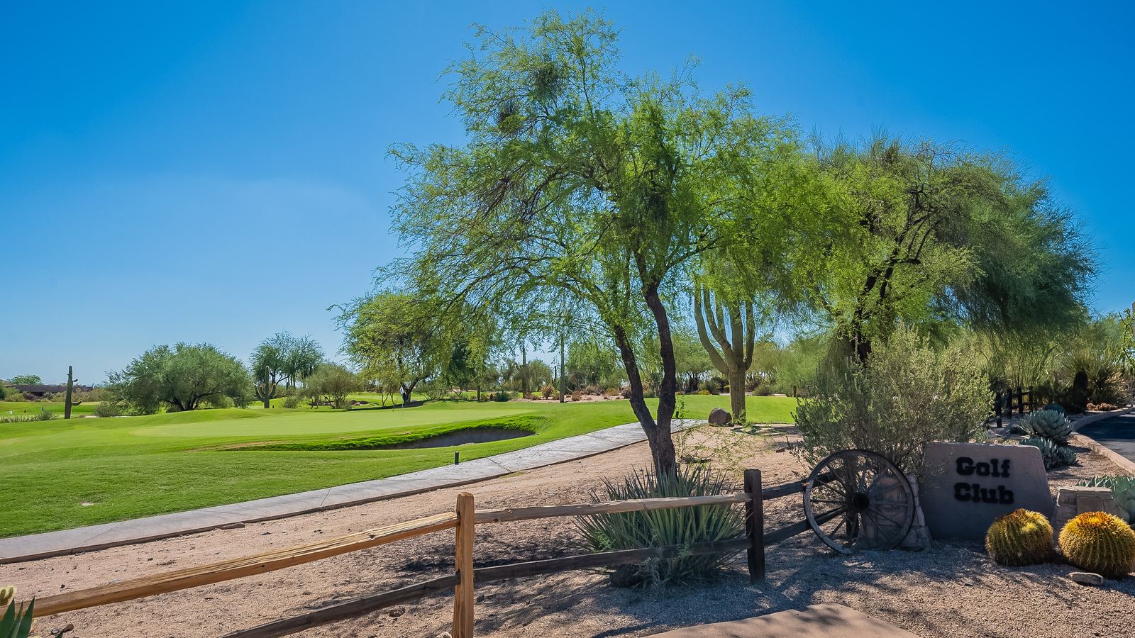Legend Trail golf course green and fairway framed by desert trees and a split-rail fence in North Scottsdale