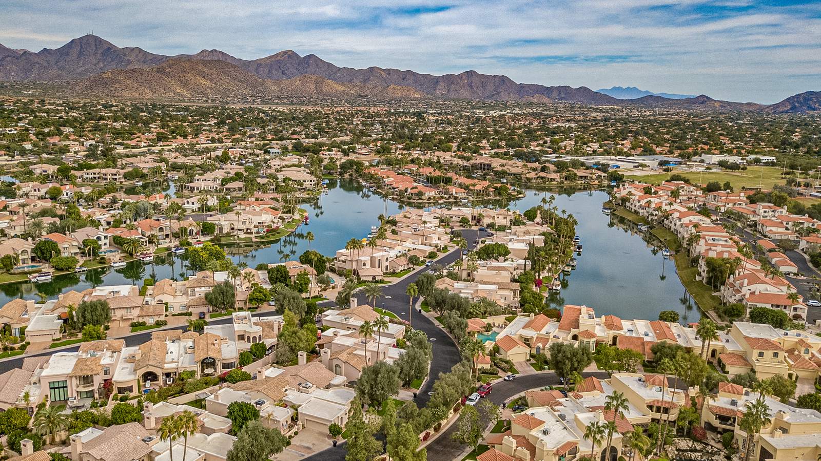 Aerial view of Scottsdale Ranch neighborhoods and lake with mountains beyond